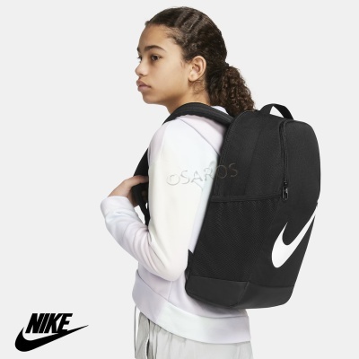 Mochila preta Nike com logo branca, vista lateral em jovem com casaco branco