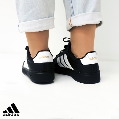 Ténis Adidas pretos com riscas brancas e calças de ganga claras