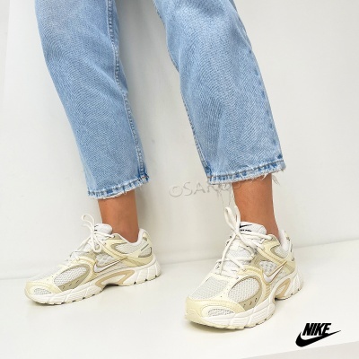 Sapatilhas desportivas Nike brancas e bege com malha e couro, usadas com calças de ganga claras.