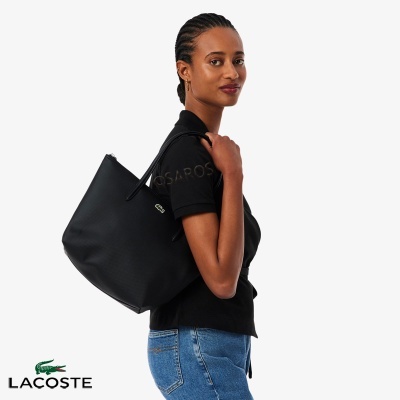 Mulher com mala de ombro preta Lacoste e roupa casual