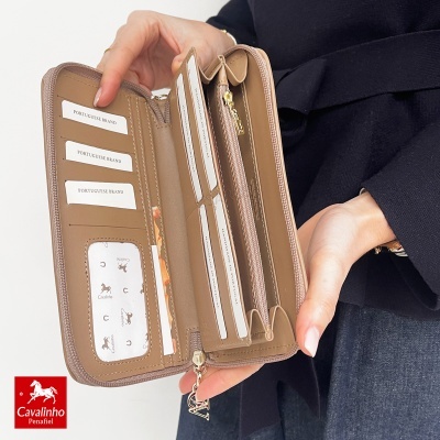 Carteira castanha aberta com vários compartimentos para cartões, em mãos femininas.