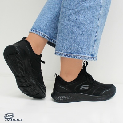 Skechers ténis pretos com sola grossa usados por pessoa com jeans azuis