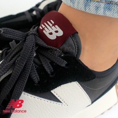 Ténis New Balance preto, branco e bordô com atacadores pretos, usados com jeans claros.