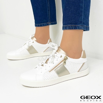 Tênis brancos com detalhes dourados e calças de ganga azuis