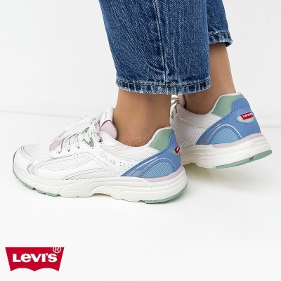 Ténis Levis brancos com detalhes verdes, azuis e rosa usados com jeans azuis