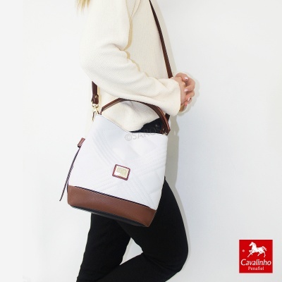Mala de ombro branca e castanha com padrão geométrico usada por mulher