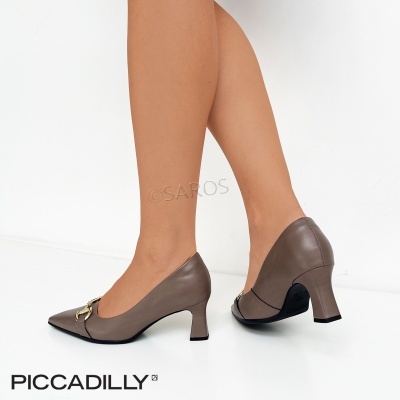 Sapatos de salto médio castanhos com detalhe dourado, em pernas femininas e fundo branco.