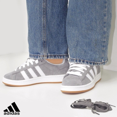 Ténis Adidas cinzentos com riscas brancas e atacadores brancos, jeans azuis, atacadores cinzentos extra no lado
