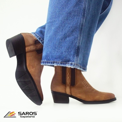 Botas em camurça castanha com salto médio preto usadas com jeans azul