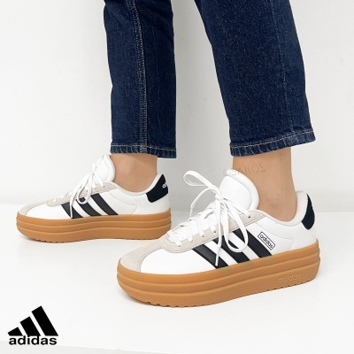 Sapatos Adidas em branco com listras pretas e sola castanha