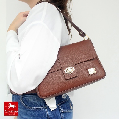 Mala castanha de pele com fecho dourado usada ao ombro