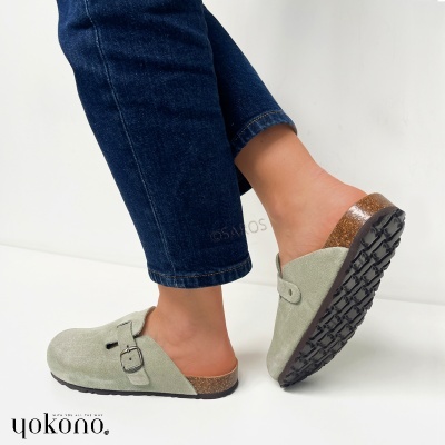 Sapatos mule camurça verde claro com sola preta e salto em cortiça usados com jeans escuros.
