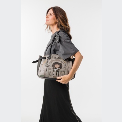 Mala cinzenta com ilustração e mulher a usá-la com roupa cinzenta e preta