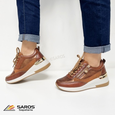 Ténis castanhos com detalhes dourados e sola branca usados com calças de ganga azul