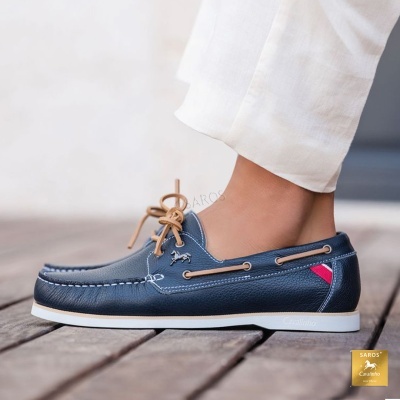 Sapato mocassim azul escuro em pele com atacadores castanhos e sola branca.