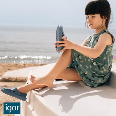 Menina calçando sapato azul claro junto ao mar com vestido verde florescente