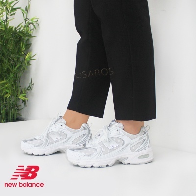 Sapatilhas New Balance brancas e prateadas com calças pretas
