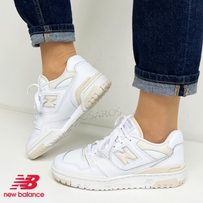 Ténis brancos New Balance com detalhes em bege claro usados com calças de ganga azul