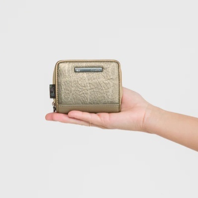Carteira dourada texturizada em mão sobre fundo cinza