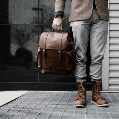 Mochila de couro castanho estilo vintage em ambiente urbano com homem segurando