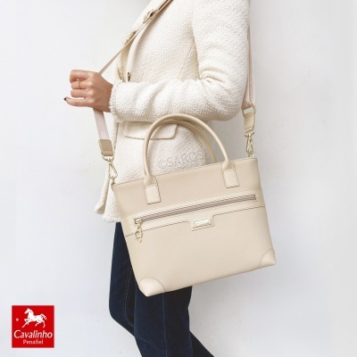 Mala bege claro com alças duplas e alça longa ajustável, com fecho zip e detalhe metálico Cavalinho, contra fundo branco