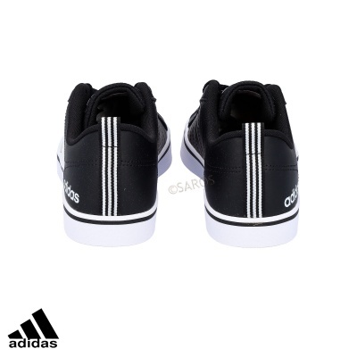 Ténis Adidas pretos com riscas brancas e sola branca vistos de trás