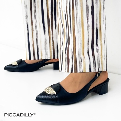 Sapatos pretos de salto baixo com detalhe dourado, calças largas com riscas verticais