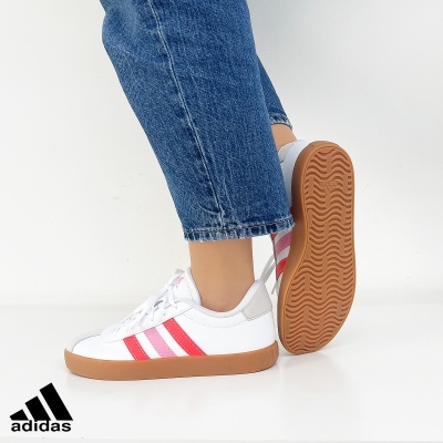 Ténis Adidas brancos com riscas cor de rosa e sola castanha usados com calças de ganga