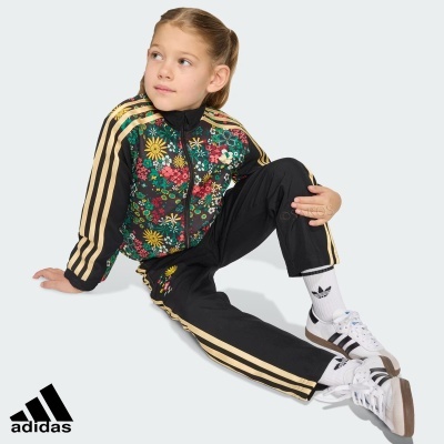 Menina com conjunto de treino Adidas preto com padrão floral e riscas douradas
