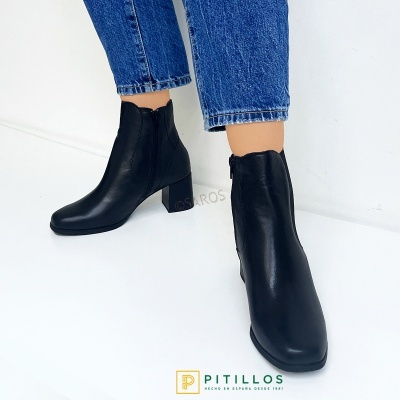 Bota feminina preta de couro com salto médio e calças de ganga azuis