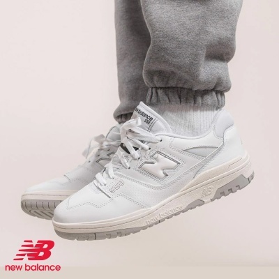 Ténis New Balance 550 brancos com sola cinza usada por pessoa com calças cinza