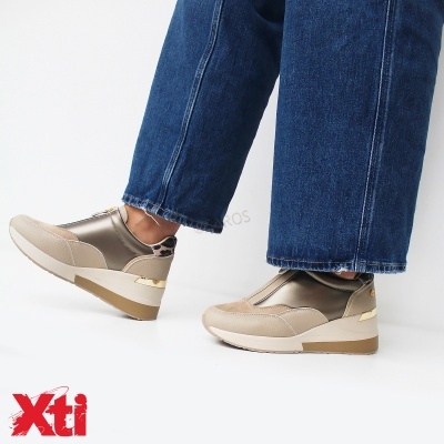 Ténis bege com detalhes metálicos dourados usados com calças de ganga azul