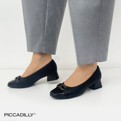 Sapatos de salto baixo pretos texturizados com detalhe metálico dourado na frente e calças cinzentas.