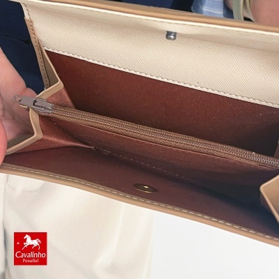 Carteira de couro bege e castanha aberta, com fechos e etiqueta vermelha Cavalinho.