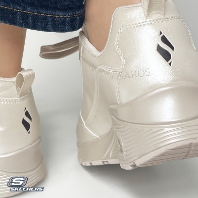 Ténis Skechers bege perolado com sola robusta e logo preto, usados com calças de ganga