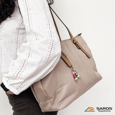 Mala bege claro com alças castanhas e chaveiro colorido pendurada no ombro