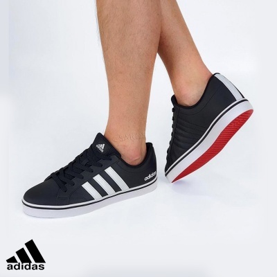 Ténis Adidas pretos com riscas brancas e sola vermelha vistos de perfil