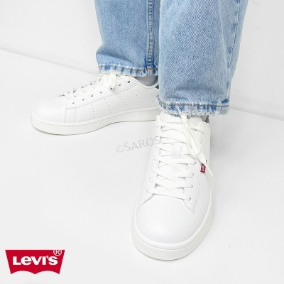 Sapatilhas brancas Levis com calças de ganga claras em fundo branco.