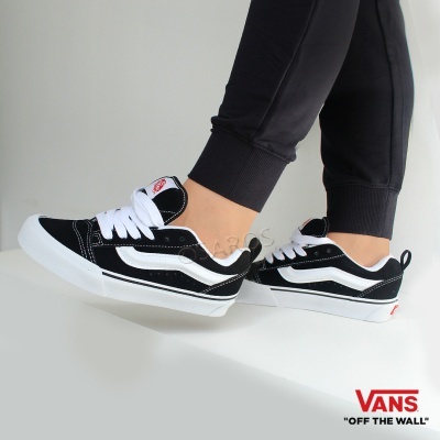 Ténis Vans pretos e brancos com sola branca e risca lateral curva