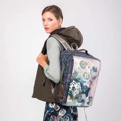 Mochila retangular padrão multicolorido em ombro de mulher com casaco verde