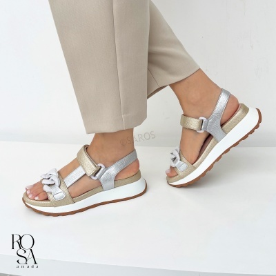 Sandálias prateadas e douradas com sola branca, usadas com calças bege