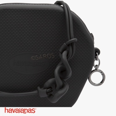 Bolsa preta da marca havaianas com textura em padrão de pequenas escamas e alça decorativa com elos segmentados.
