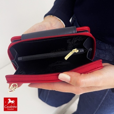 Carteira vermelha com interior preto aberta e mãos a segurá-la