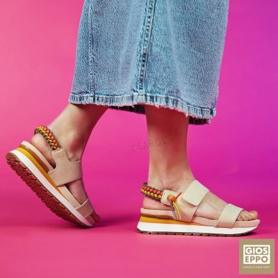 Sandálias Gioseppo em tecido bege com cordões coloridos e sola branca sobre fundo rosa.