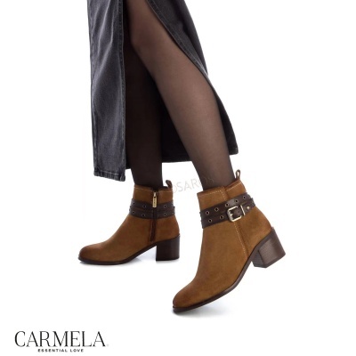 Botins castanhos em camurça com tiras e fivela metálica usados com meia preta e saia preta