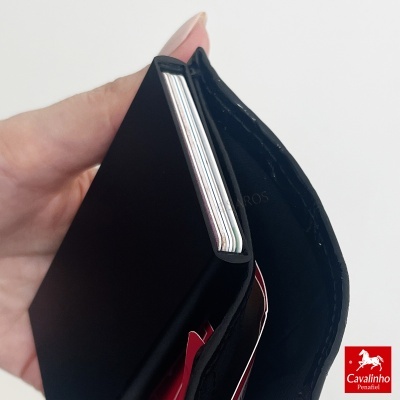 Carteira preta em couro com divisórias para cartões, segurada por mão feminina