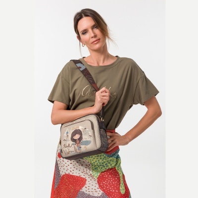 Mulher com t-shirt verde-oliva e saia colorida a segurar mala bege com ilustração e texto