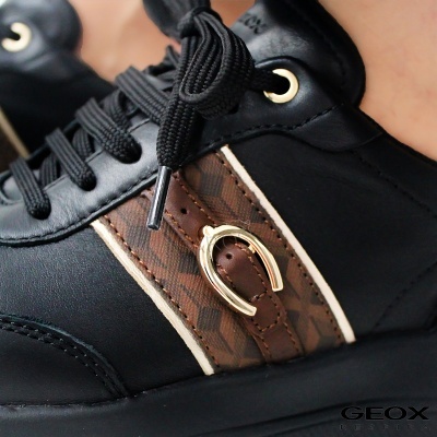 Ténis pretos com detalhe lateral castanho e bege e fivela dourada em ferradura.