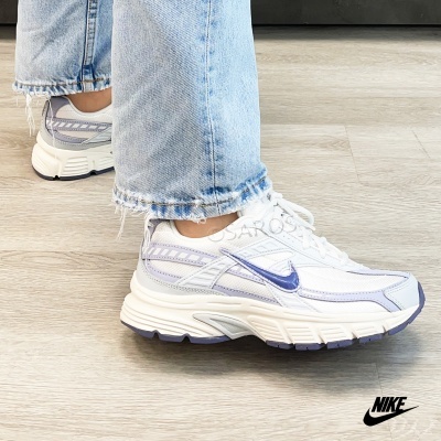 Ténis Nike brancos com detalhes lilás e azul usados com calças de ganga