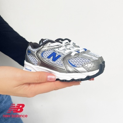 Ténis infantis New Balance cinza e azul segurados por uma mão